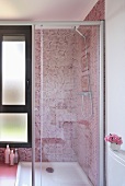 A bathroom with a glazed shower unit and red mosaic tiles