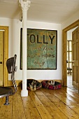 An anteroom with a white metal pillar and two dogs in baskets on the rustic floorboards