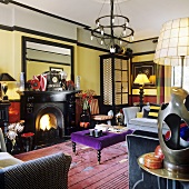 A brightly coloured living room with a fireplace, upholstered furniture and a wrought iron chandelier