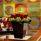 A flower arrangement of different coloured roses in a black, shiny vase