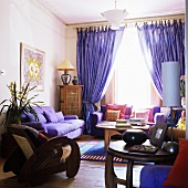 A living room with upholstered furniture and purple curtains at the window