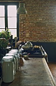 A rustic dining room with a brick wall and a kitchen counter with storage jars
