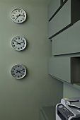 Uhren mit verschiedenen Zeitzonen auf grauer Wand