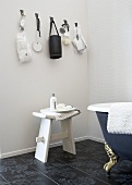 Bathroom corner with white stool in front of an antique bathtub in vintage style