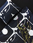 Blumenzweig auf schwarz-weiss gemusterter Bettdecke