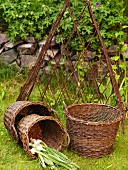 A three piece wicker basket set with fresh garlic in front of a metal trellis
