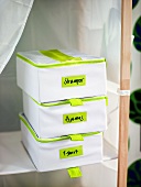 Labelled plastic boxes on a shelf covered in white fabric