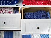 Pads and patterned fabric in drawers with white wooden fronts