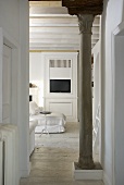 Hallway with antique Greek columns and a view into an open plan design living room to a white cupboard