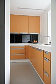 Blick durch Türöffnung auf moderne offene Küche mit orangefarbenen Fronten