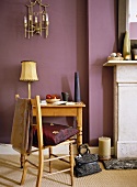 Ländlicher Holzstuhl und Tisch vor auberginefarbener Wand