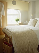 Double bed with woollen throw in white bedroom