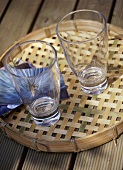 A detail of two glasses on a bamboo tray set on a wooden table,