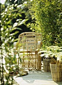 Sessel und Pflanzenbehälter aus Bambus auf Holzboden im Garten