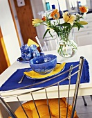 Blaues Gedeck und Blumenstrauss auf weißem Tisch