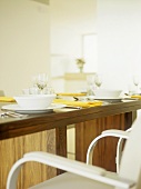 Detail of dining room with table setting and yellow napkins on wooden table.
