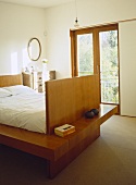 Schlittenbett aus Holz und umlaufender Ablage vor Balkonfenster