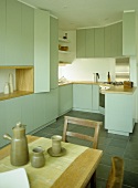 Dining table and chairs in kitchen with green fitted units