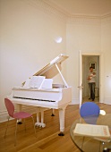 Weisses Klavier mit rotem Stuhl und Vater mit Kind in offener Zimmertür