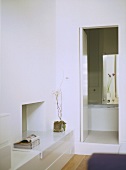 A detail of a modern, white bedroom with view of en suite bathroom,