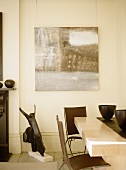 Elegantes Esszimmer mit Stühlen aus Metall und braunen Lederflächen und modernes Bild an Wand