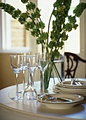 Close up of cream crockery wine glasses and flower arrangement on table