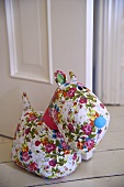 A stuffed toy made from a floral patterned material being used as a door stop