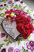 Red heart-shaped cushions with fabric flowers and a bunch of roses on plaid