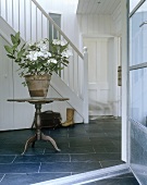 Flower pot on a wooden side table in a white stairwell of a country home