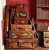 Stapel von alten Lederkoffern neben Regal mit alten Büchern