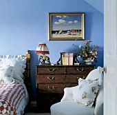 Blaues Schlafzimmer mit antiker Kommode aus dunklem Holz
