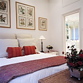 Grosses Schlafzimmer mit Bildern an der Wand und rote und weiße Kissen auf dem Bett