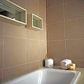 weiße Badewanne un Regale mit Spiegelrückwand in beige gefliestem Badezimmer