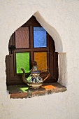 Keramik Kaffeekanne auf Fensterbank eines maurischen Fensters mit bunten Gläsern