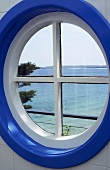 Blick auf das Meer durch rundes blau-weisses Fenster
