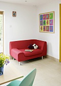 Rotes modernes Sofa unter Bild in Zimmerecke mit hellem Fliesenboden