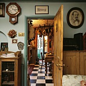 Offene Holztür mit darüber hängender Wanduhr, öffnet den Blick zu einer traditionellen Küche mit schwarz-weiss gefliestem Fußboden