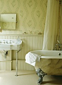 Cremefarbenes, tapeziertes Badezimmer mit marmorierter Clawfoot-Badewanne und halb hoher Holzvertäfelung