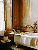 Traditionelles Landhaus-Badezimmer mit Holzvertäfelung, Clawfoot-Badewanne und einem Emailkrug auf einem Holzschemel
