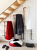 Aufgehängte Badetücher, Badetasche und eine Waage in einem gefliesten Badezimmer