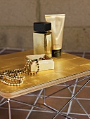 A jewellery box and a pearl necklace with a golden perfume bottle and a tube of cream