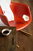 A red rocking chair with a miniature replica version in white and a cup of coffee on a wooden table
