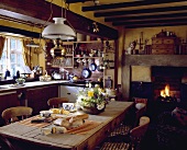 Viktorianische Lampe aus Messing und Glas über einem Tisch aus Kiefer Tisch und ein Kamin in einer Landhausküche