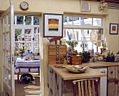 Rustikale Holzarbeitsplatte und Schränke in einer Landhaus-Küche mit Glastür zum Esszimmer im Wintergarten