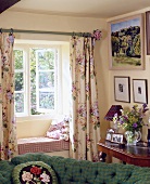 Vorhänge mit Blumenmuster am Fenster und eine kleine Bank in der Fensternische