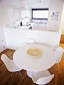 Esstisch und Schalenstühle in Weiß aus Bauhauszeit vor offener moderner Küche