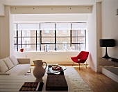 An open-plan, modern living room with a mixture of styles - a light-coloured sofa and a red armchair