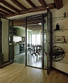 Wohnzimmer mit Balkendecke, Holzboden und modernen Glastüren zur Küche und Esszimmer