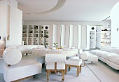 weiße Leder-Sitzbank und Stühle am runden Tisch in einem weissen Wohnzimmer mit Sofa und Paravent