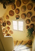 Sammlung von Strohhüten an den Wänden in dem Treppenhaus eines französischen Landhauses
